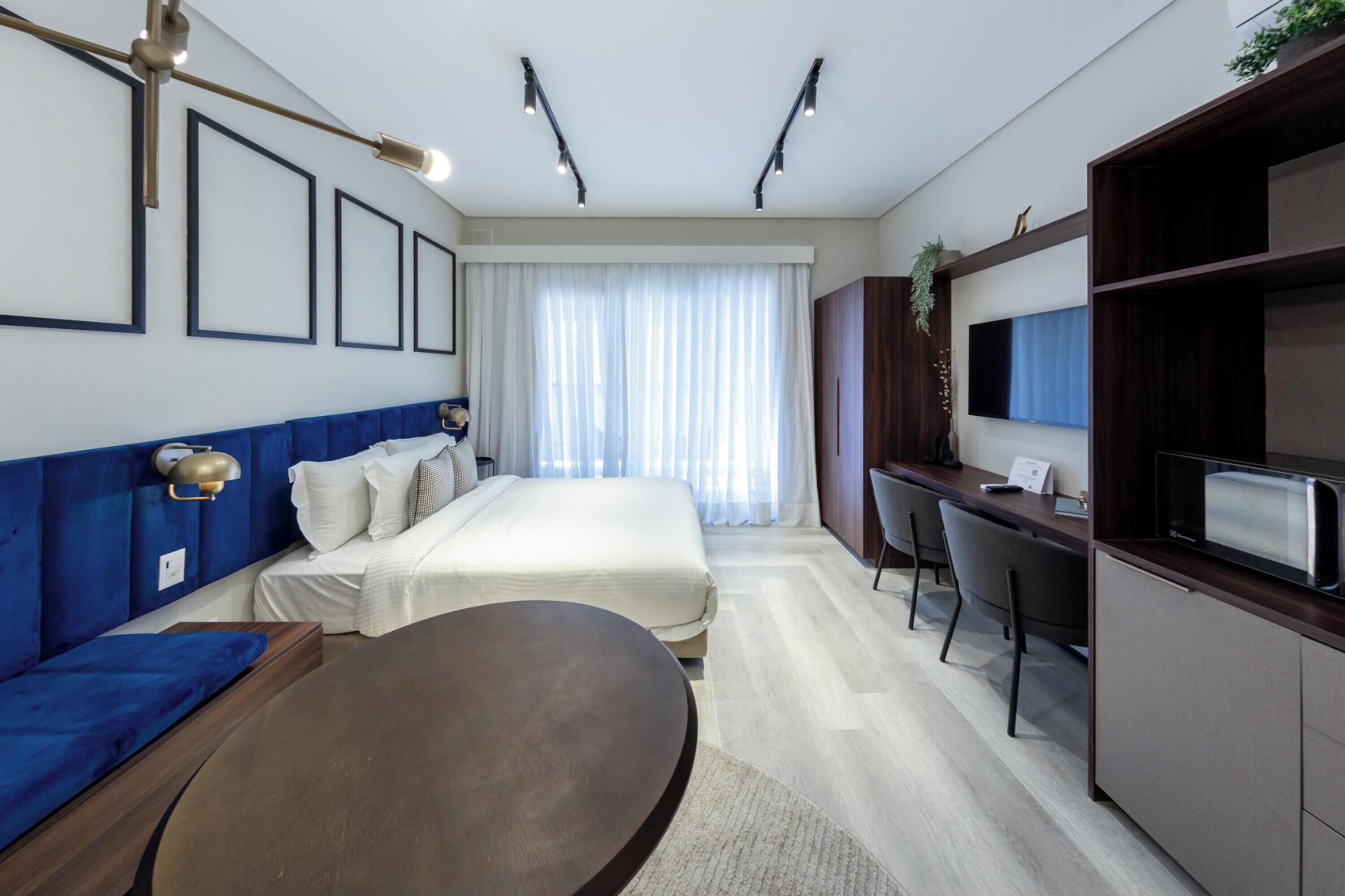 Una habitación de hotel moderna con cama, escritorio, sofá y televisor.