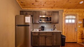 A compact kitchen with a stainless steel refrigerator, a microwave, and a coffee maker on the countertop. - Grandview Cabin Suite 24-Hot Tub (McHenry)