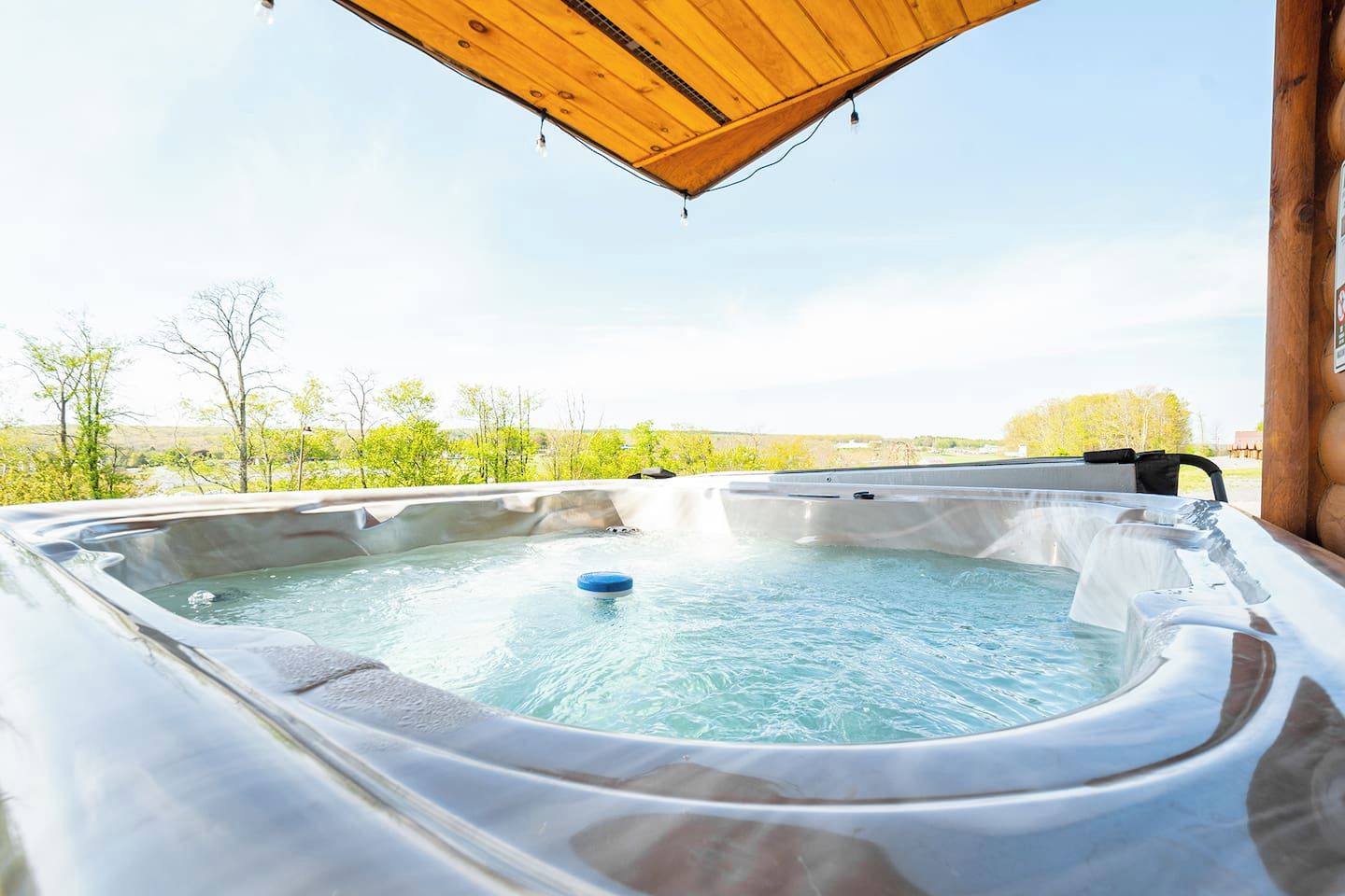 A hot tub with a wooden roof overhead, surrounded by a natural landscape.