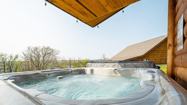 A hot tub in a log cabin with a wooden roof and a view of the surrounding landscape. - Grandview Cabin Suite 27-Hot Tub, Dog Friendly (McHenry)