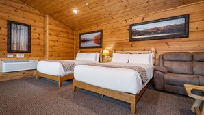 A wooden cabin room with two beds, a brown leather chair, and two framed pictures on the walls. - Grandview Cabin Suite 29-Full Kitchen (McHenry)