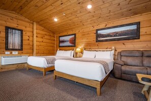 A wooden cabin room with two beds, a couch, and a fireplace. - Grandview Cabin Suite 29-Full Kitchen (McHenry)