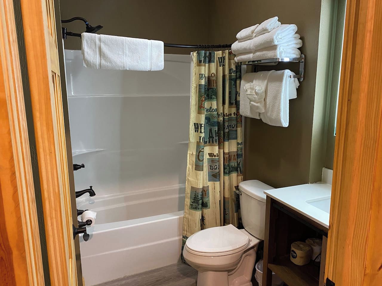 A bathroom with a bathtub, toilet, and a shower curtain with a travel-themed pattern.