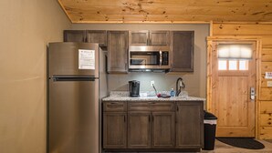 A compact kitchen with a stainless steel refrigerator, a microwave, and wooden cabinets. - Grandview Cabin Suite 30-Hot Tub, Dog Friendly (McHenry)