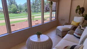 A room with a large window, wicker furniture, and a small potted plant. - Bright Sedona Retreat with Castle Rock Views (Sedona)