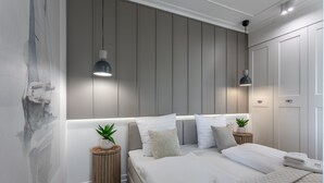 Un dormitorio moderno con una cama grande, dos mesitas de noche con plantas y un aplique de pared.