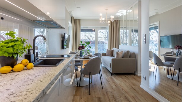 Una cocina moderna con una isla grande, comedor con sillas, un sofá y televisión en una sala separada.