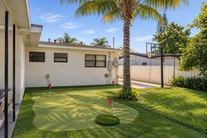 A residential property with a well-maintained lawn, a palm tree, and a basketball hoop. - Casa Palma | Pool + Hot Tub + Mini Golf (Miami)