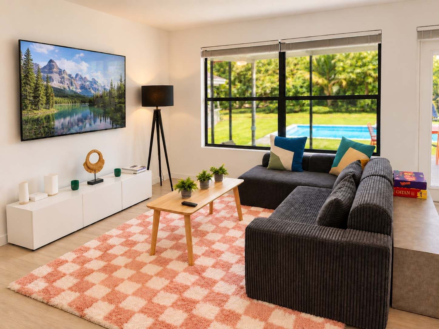 Una sala moderna con un ventanal grande, un juego de sofá, una mesa de centro y un televisor montado.