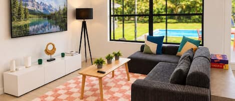 Una sala moderna con un ventanal grande, un juego de sofá, una mesa de centro y un televisor montado.