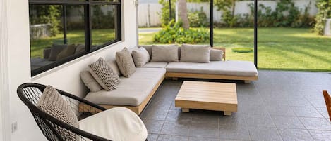 A modern outdoor living space with a sectional sofa, a wooden coffee table, and a wicker chair.