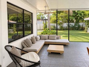 A modern outdoor living space with a sectional sofa, a wooden coffee table, and a wicker chair. - Hot-Tub, Pool, Basketball, Fire Pit, Pong | Casa (Miami)