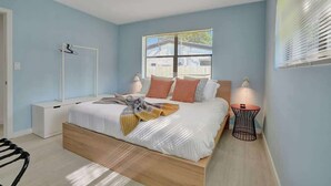 A bedroom with a bed, bedside tables, a chair, and a window with blinds.