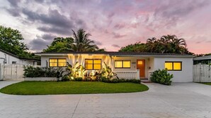 A modern two-story house with a well-maintained lawn, a driveway, and a white fence.