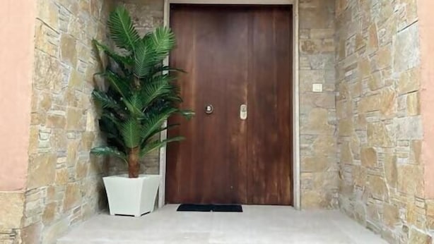 A stone-walled entrance with a wooden door, a potted plant, and a small staircase leading up to the door. - Excepcional Chalet en Perbes (Perbes (San Pedro))
