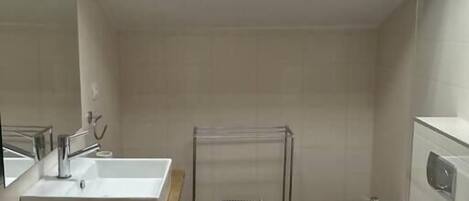 A modern bathroom with a skylight, a large sink, a toilet, and a bidet.