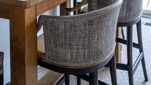 A wooden dining table with wicker chairs, a potted plant, and decorative items on the table. - Waterfront Condo in Spring Lake-Blissful Blue Waterfront (Spring Lake)