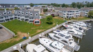 A marina with boats docked, a grassy area with a building, and a residential neighborhood in the background. - Waterfront Condo in Spring Lake-Blissful Blue Waterfront (Spring Lake)