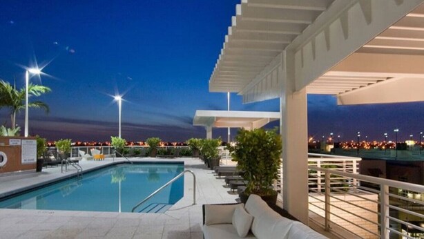 A pool area with a view of the city at dusk. - Lovely apt in the heart Midtown (Miami)