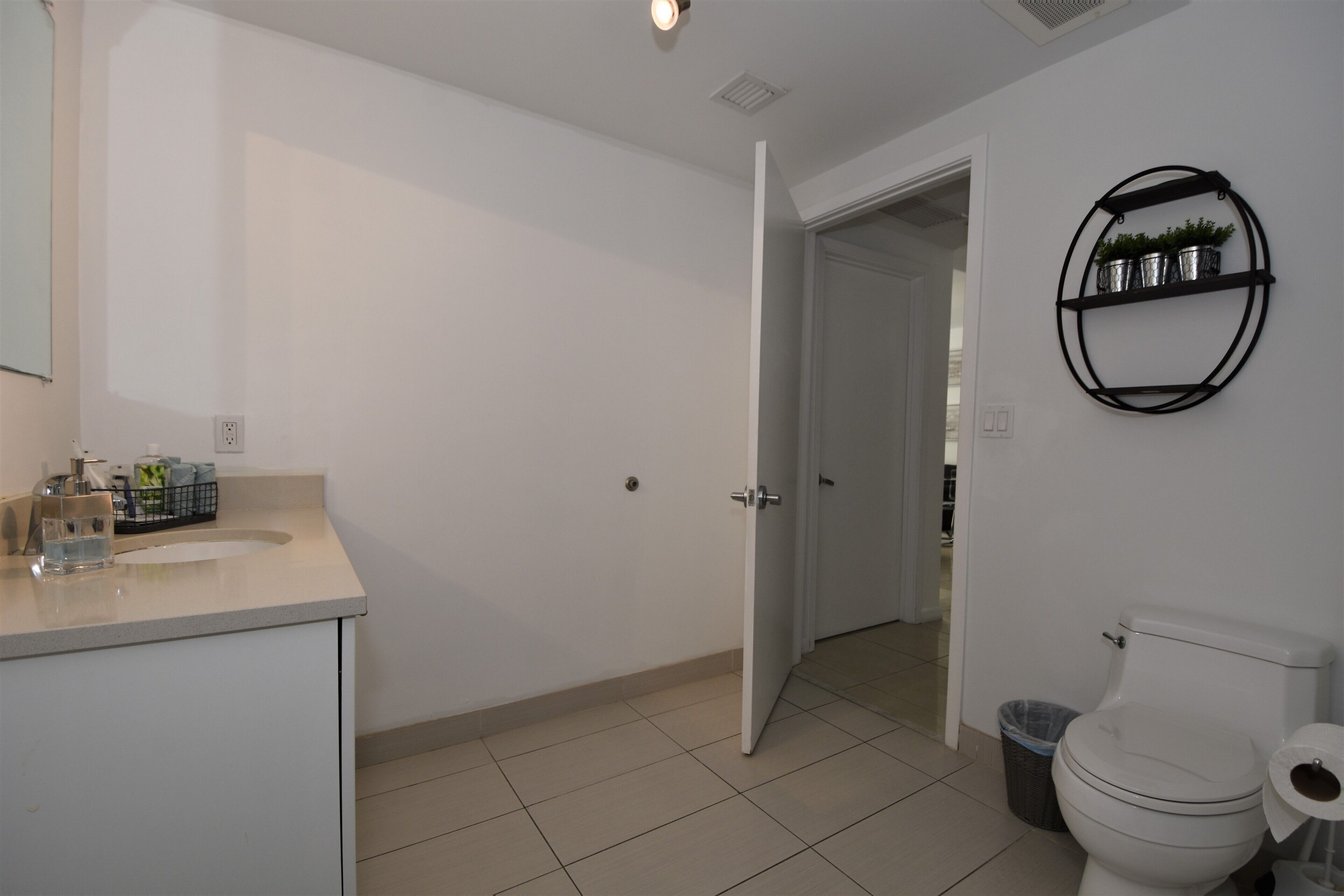 Ein Badezimmer mit Toilette, Waschbecken und einem Regal mit Pflanzen.