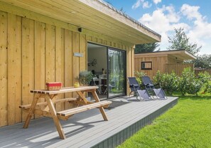 Eine Holzterrasse mit einem Picknicktisch und zwei Liegestühlen.