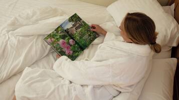 Una persona leyendo un libro acostada en la cama.