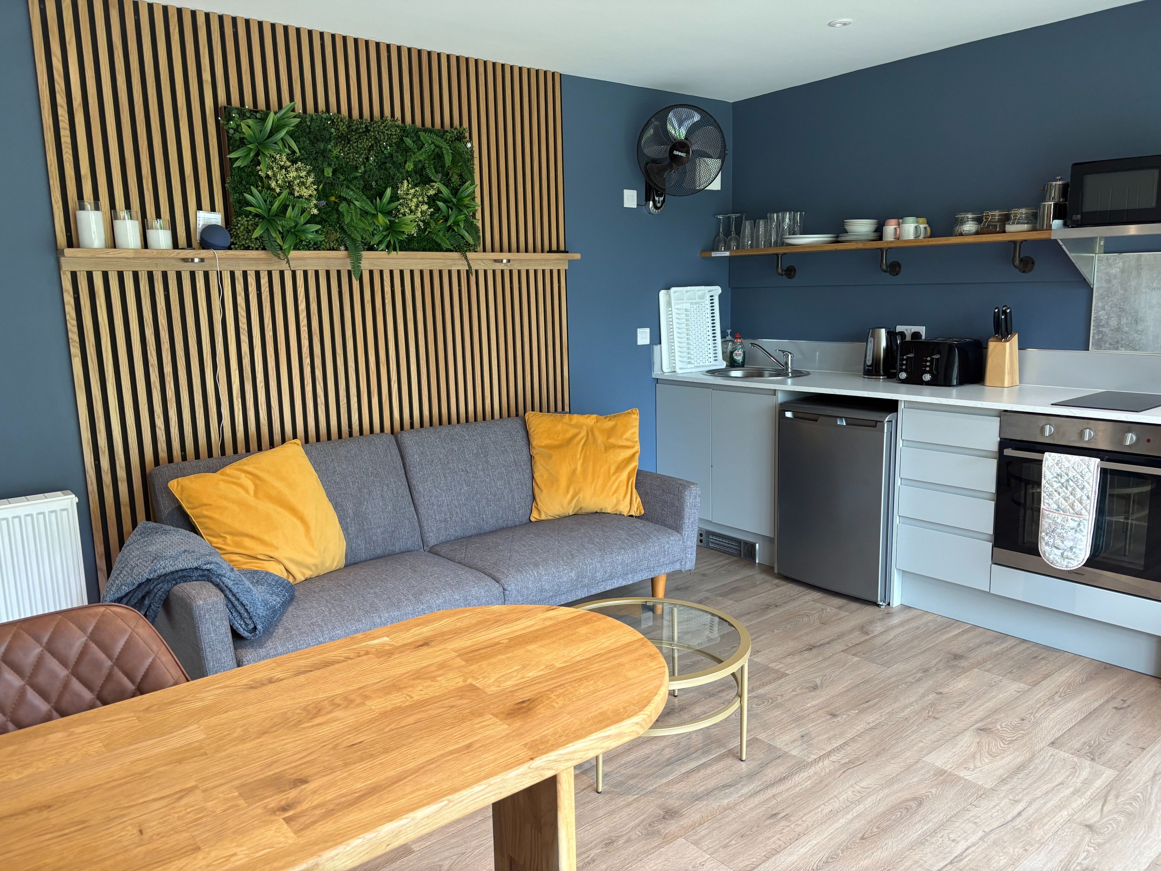 A modern kitchen with a built-in oven, microwave, and a wooden dining table.