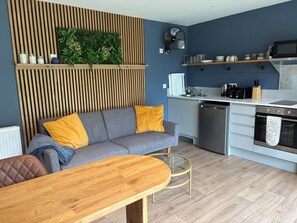 Une cuisine moderne équipée d’un four encastré, d’un four à micro-ondes et d’une table à manger en bois.