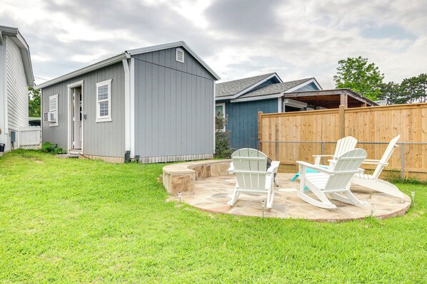 A backyard with a patio, two Adirondack chairs, and a small shed.