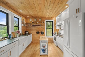 A modern kitchen with wooden walls, white cabinets, and a large window. - Jewelbox Cabin, Rolling hills escape in Cataldo (Cataldo)