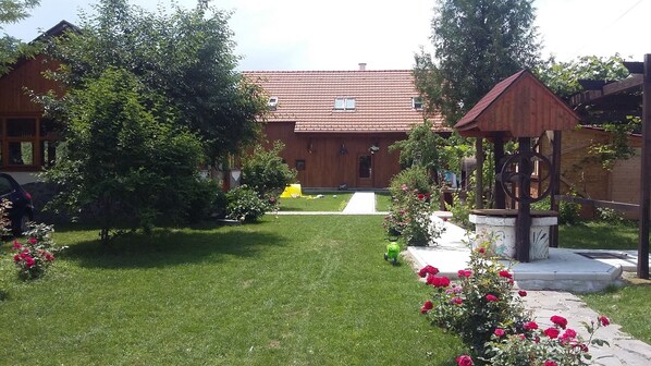 A garden with a gazebo, a lawn, and a building with a red-tiled roof.