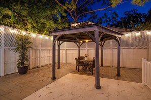 Un patio couvert agrémenté d’une pergola, d’une table à manger avec des chaises et d’une plante en pot.