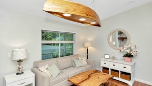 A living room with a sofa, coffee table, side table, lamp, mirror, and a window with blinds. - 1 Mi to Beach: Charming Largo Home w/ Private Pool (Largo)