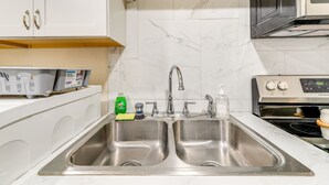 A kitchen with a double stainless steel sink, a microwave, and a stove. - Secluded Newport Getaway w/ Fire Pit & Grill! (Newport)