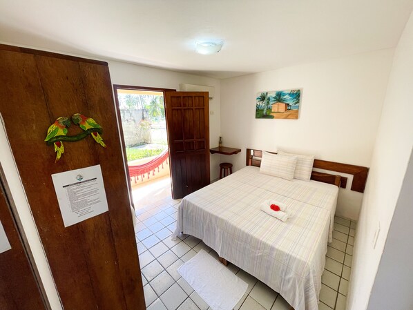 A bedroom with a bed, a wooden door, a small table, and a painting on the wall.