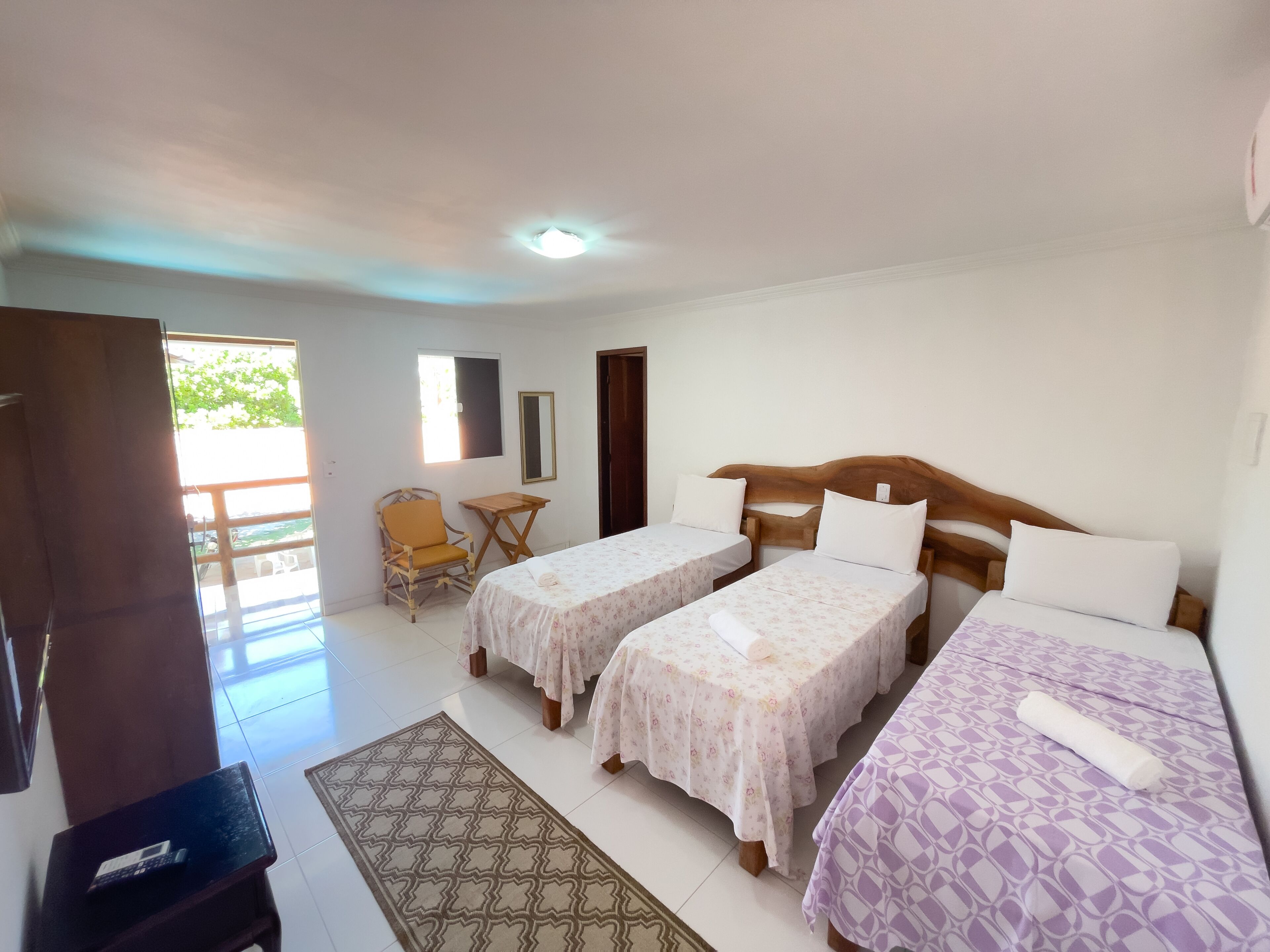 Habitación con dos camas, una silla, una mesita y una puerta que da al exterior.