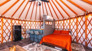 Una yurta con una cama, una pequeña cocina y un espacio para sentarse.