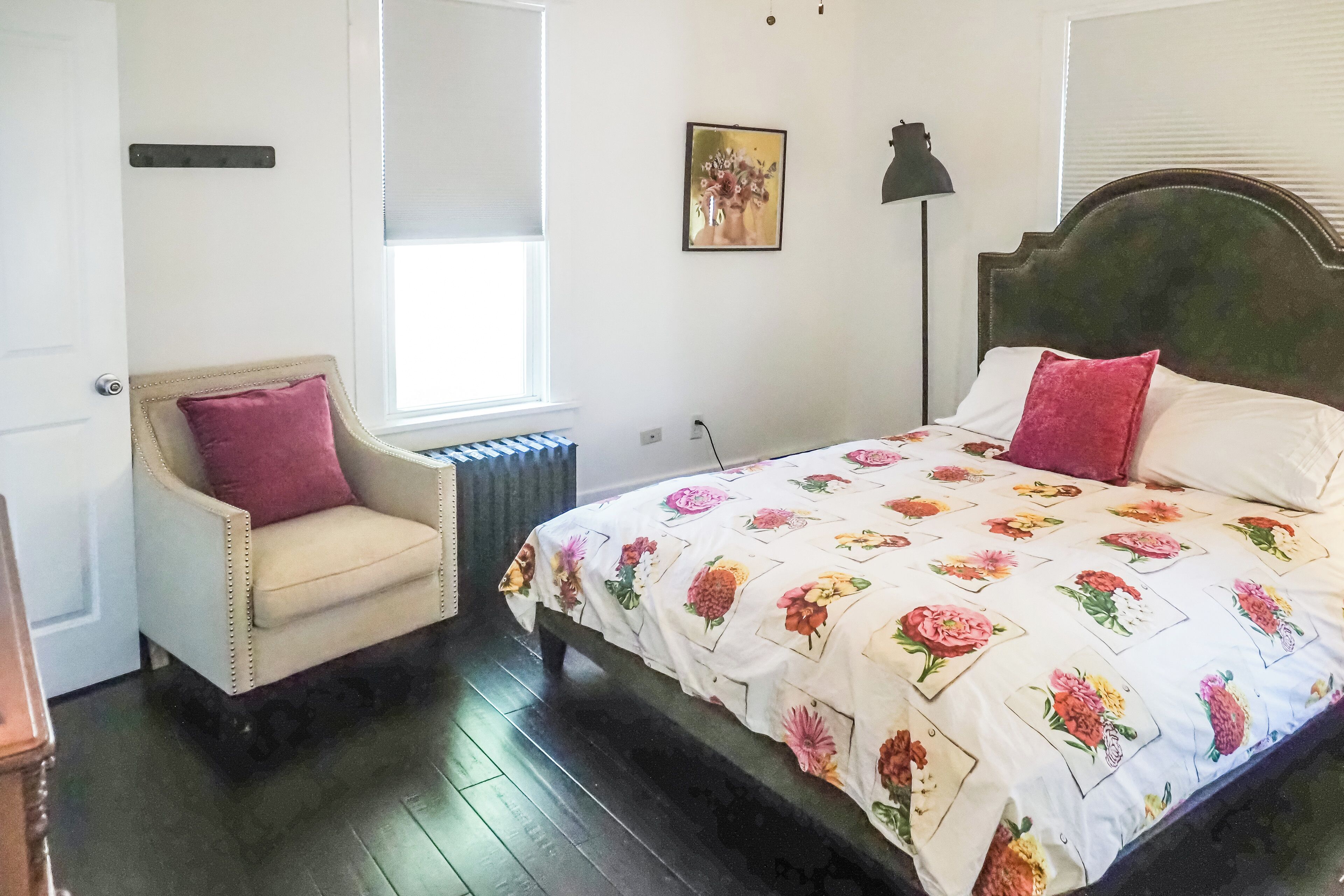 Une chambre à coucher comprenant un lit, une chaise, un radiateur, une fenêtre et un tableau accroché au mur.