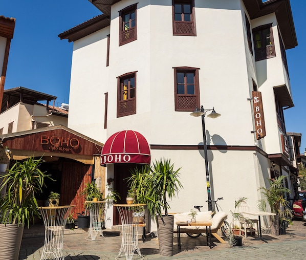 A building with a sign reading "BOHO cafe & bar" and outdoor seating with tables and chairs. - Boho Oldtown Hostel (Antalya)
