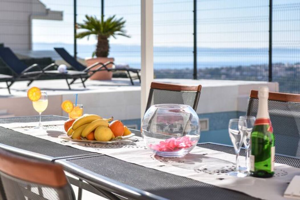 A dining table with a fruit bowl, a glass of drink, and a bottle of water.