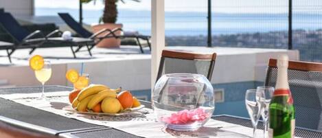 A dining table with a fruit bowl, a glass of drink, and a bottle of water.