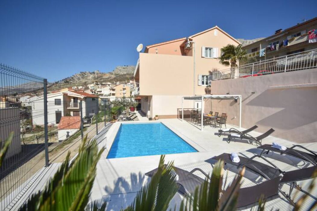 A swimming pool with lounge chairs and a building with a satellite dish.