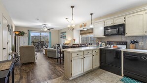 A spacious kitchen with a large island, black appliances, and light-colored cabinetry.