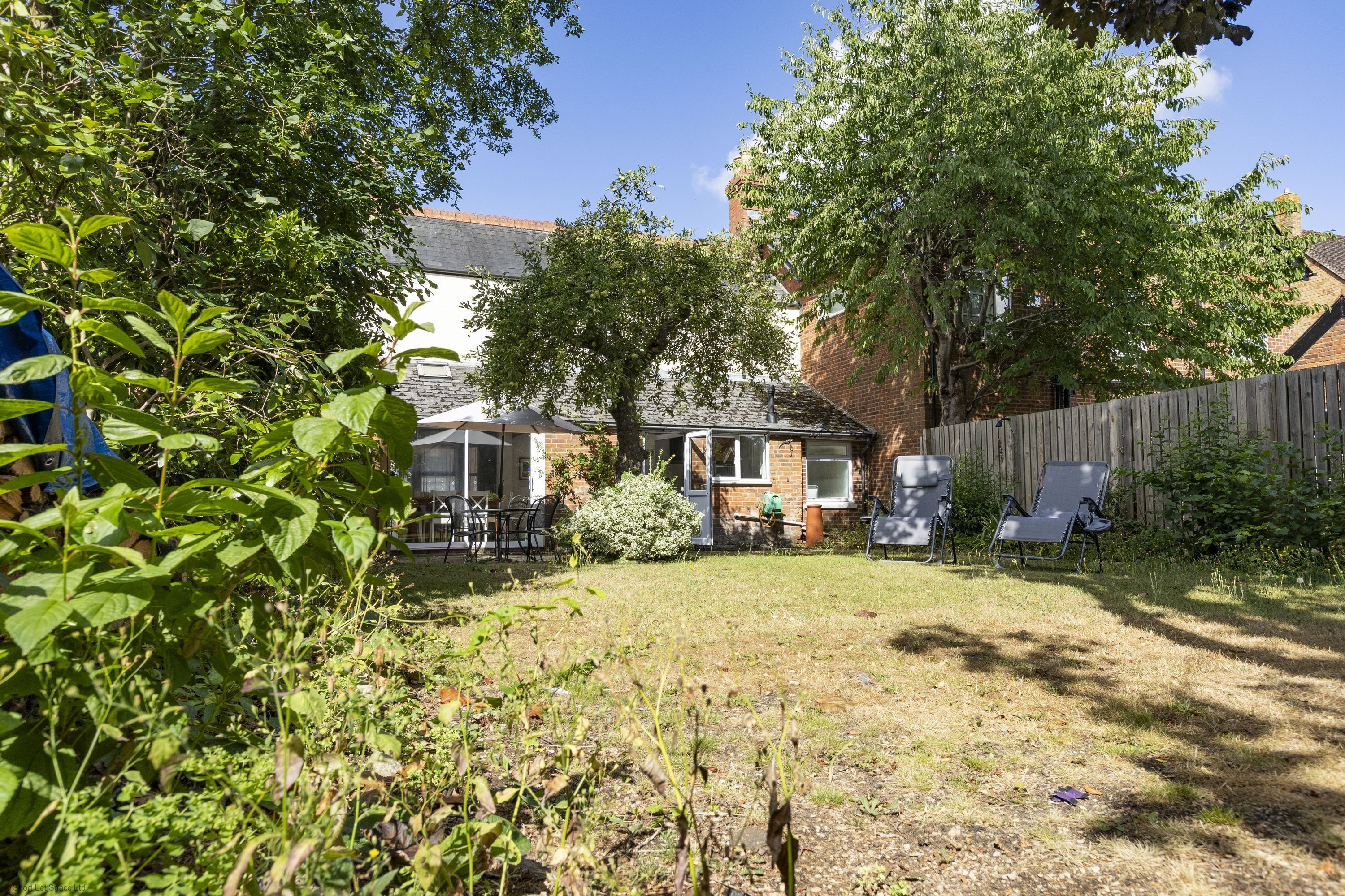 A backyard with a patio, a tree, and a fence.