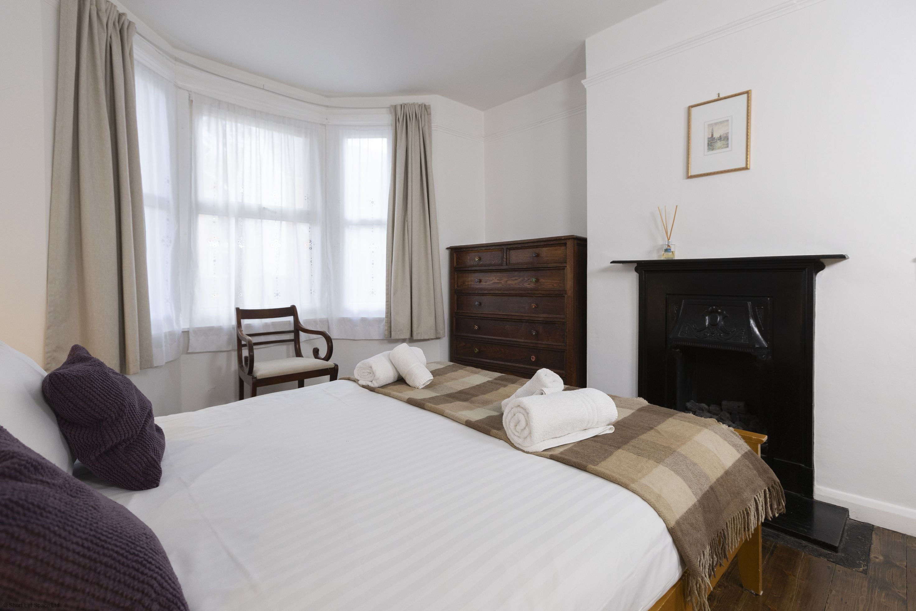 Een hotelkamer met een groot bed, een houten dressoir, een stoel en een open haard.