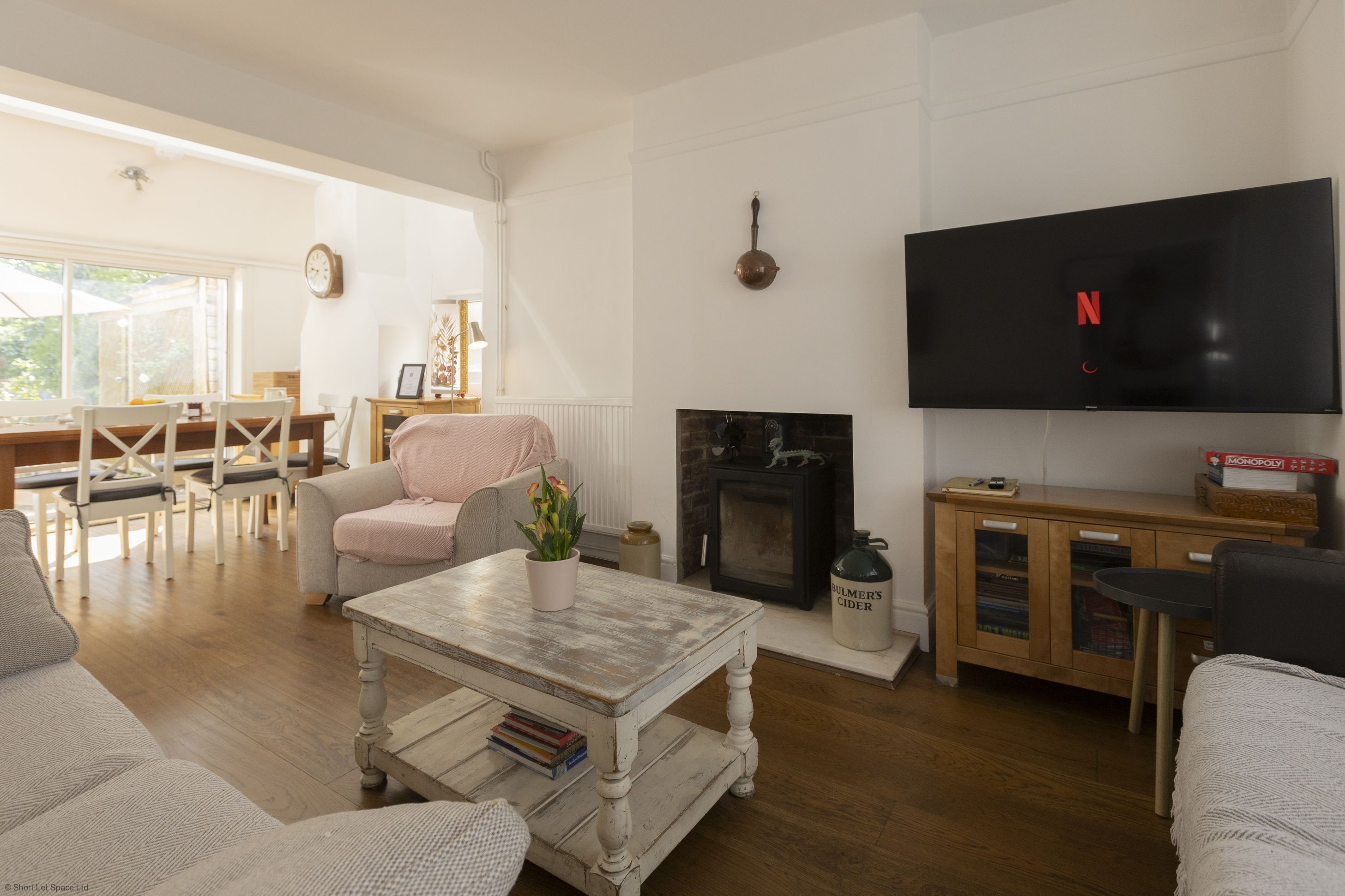 A living room with a fireplace, a television, and a dining area with a table and chairs.