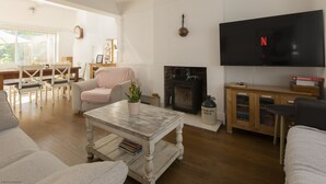 A living room with a fireplace, a television, and a dining area with a table and chairs.