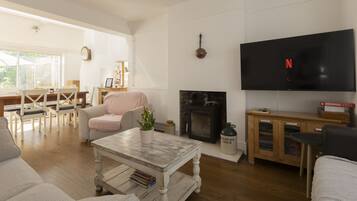 A living room with a fireplace, a television, and a dining area with a table and chairs.