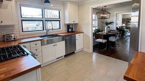 Eine moderne Küche mit weißen Schränken, einer Holz Arbeitsplatte und Blick zum Essbereich.