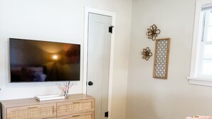Ein Schlafzimmer mit Bett, Kommode, Fernseher und Tür.